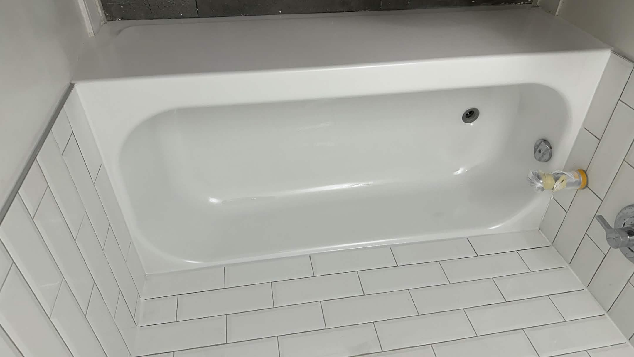 Glossy white bathtub with subway tile